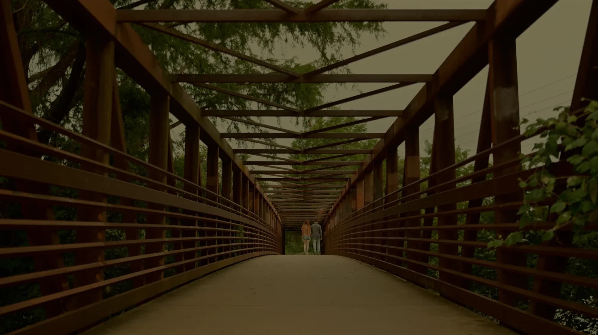 A couple walking across a bridge — still from ‘Ven